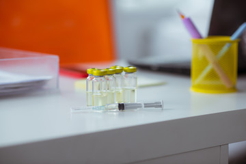 Close up of medical syringe lying near ampoules with medicine