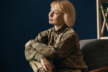 Close up portrait of female soldier. Woman in military uniform waiting for coming home. In doctor's consultation, depressed and having problems with mental health and emotions, PTSD, rehabilitation.