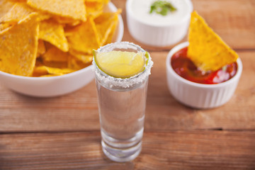 Tequila shot with lime and sea salt on wooden table