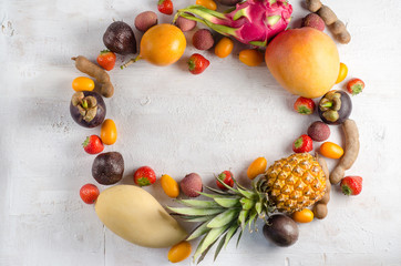 Healthy eating, varieity of fruits on a white background in a frame with copy space, vertical top view. Exotic fruits