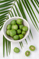 Mini kiwi on a white plate. Small exotic fruits on white background.