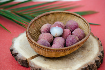 Fresh fruit lychee on a wicker basket on red background