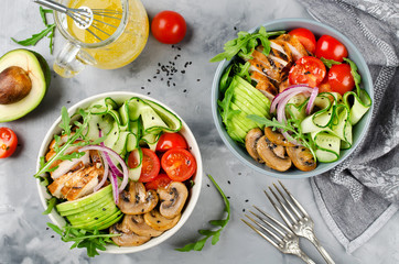 Healthy salad bowl with chicken, mushrooms, tomatoes, cucumbers, avocado and arugula