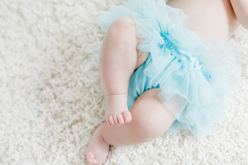 Close-up of legs and feet of baby girl on white background wearing turquoise tutu skirt. © Irina Schmidt