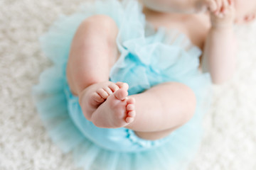 Close-up of legs and feet of baby girl on white background wearing turquoise tutu skirt. © Irina Schmidt
