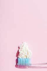 top view of toothbrush with toothpaste made of whipped cream on pink with copy space