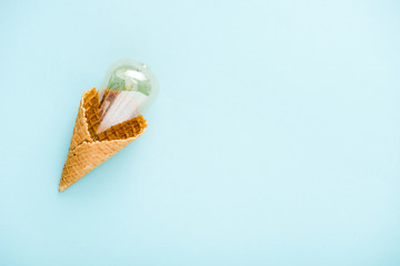 top view of glass lightbulb in ice cream cone isolated on blue with copy space