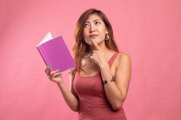 Young Asian woman with a book is thinking.