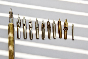 metal tips for the ink pen on a white background in solar rays. stationery on white desk close up...
