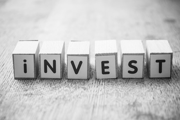 Closeup of word on wooden cube on wooden desk background concept - Invest