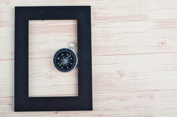 top view empty photo frame and compass on wooden background