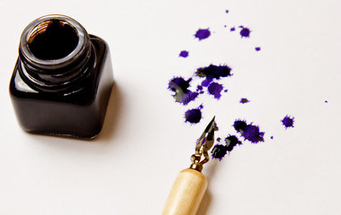 ink stain drawn with an ink pen on a white paper sheet with inkwell. blot and stationery close up...