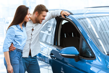 Loving the inside. Happy young couple looking at the inside of the new car at the car salon...