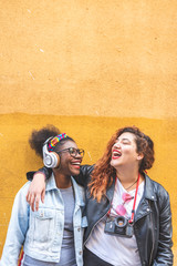 Two Teenage Latin Girls Standing Together Over a Yellow Wall.