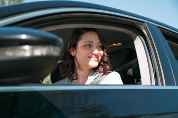 Businesswoman driving a car and looking through car window