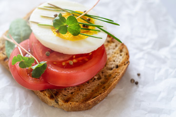 Toast of unleavened bread with tomato, spinach, egg and microgreen