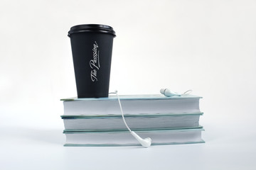 Audio book concept. Headphones, black cup of coffee and stack of books on white background. Copy space for text