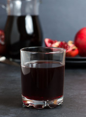 Pomegranate, pomegranate juice in a glass Cup. Dark background. Side view. The concept of therapeutic nutrition