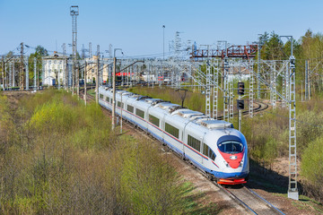 Fototapeta premium Modern high-speed train moves through the station at spring morning time.