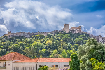 Fototapeta na wymiar View of the fortress and Luso Roman castle of Óbidos, with buildings of Portuguese vernacular architecture and sky with clouds, in Portugal