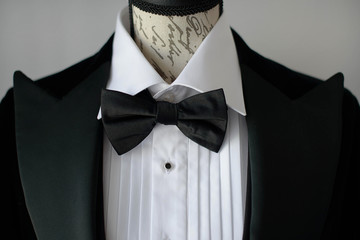 Cropped shot of elegant black tie suit with white shirt and silk bow tie on  mannequin torso or a...