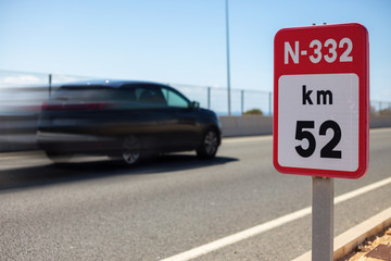 A sign with the number of National Road 332 in Spain and a black car that drives very fast.