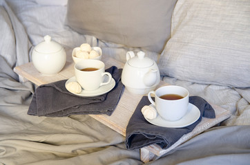 Fototapeta na wymiar Breakfast In Bed : teapot, two cup of tea and swetts meringue on wooden tray. Good morning scenery background. Scandinavian style.