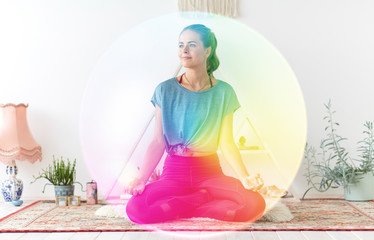 Obraz na płótnie Canvas mindfulness, spirituality and healthy lifestyle concept - woman meditating in lotus pose at yoga studio over rainbow aura