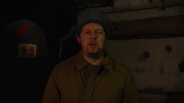 Russian man in a hat with earflaps, talking on the phone in a dark basement and decides matters of national importance.