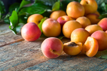 Apricots with leaves on old wooden table .