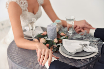 Obraz na płótnie Canvas wedding couple of young people bride and groom, holding hands, enjoying a delicious meal together, served table close up view