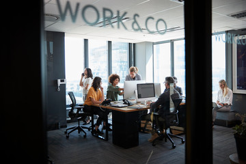 Creative business team working in a casual office, seen through glass wall with text on it