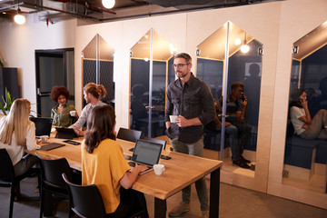 Creative business colleagues drinking coffee and talking in their office canteen