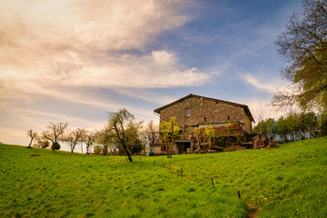 Plakat Panorama of green hills in Orobie mountains with old house built in stone.
