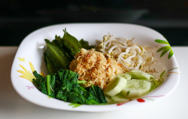 Sayur urap on black background.  Cooked vegetables with spiced grated coconut. Indonesian traditional food.