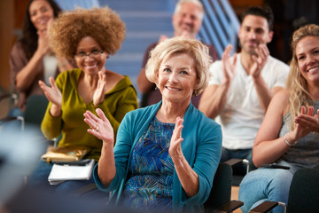 Group Attending Neighborhood Meeting Applauding Speaker In Community Center