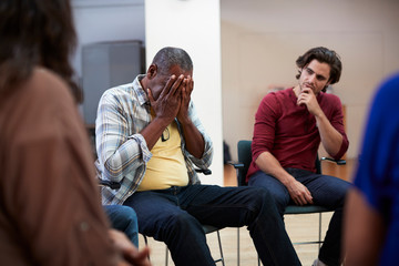 Unhappy Man Attending Self Help Therapy Group Meeting In Community Center