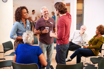 Group Of People Socializing After Meeting In Community Center - obrazy, fototapety, plakaty