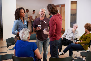 Group Of People Socializing After Meeting In Community Center