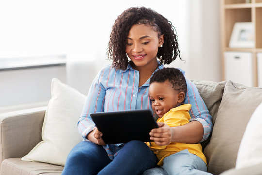 family, motherhood and technology concept - happy african american mother using tablet computer with little baby son at home