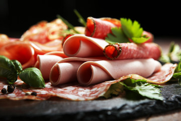 Food tray with delicious salami, pieces of sliced ham, sausages,salad and vegetable. Meat platter...