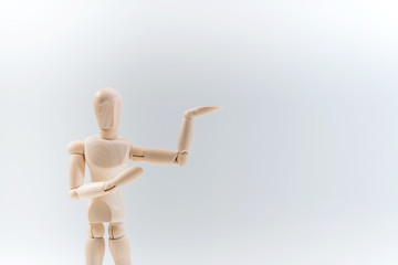 Wooden dummy proudly presents some invisible thing, isolated on white background, copy space for your object or text
