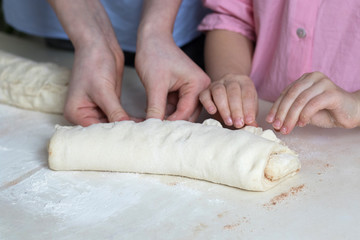 Children mold cheesecakes from dough. Kitchen table in flour. Warm relationships children