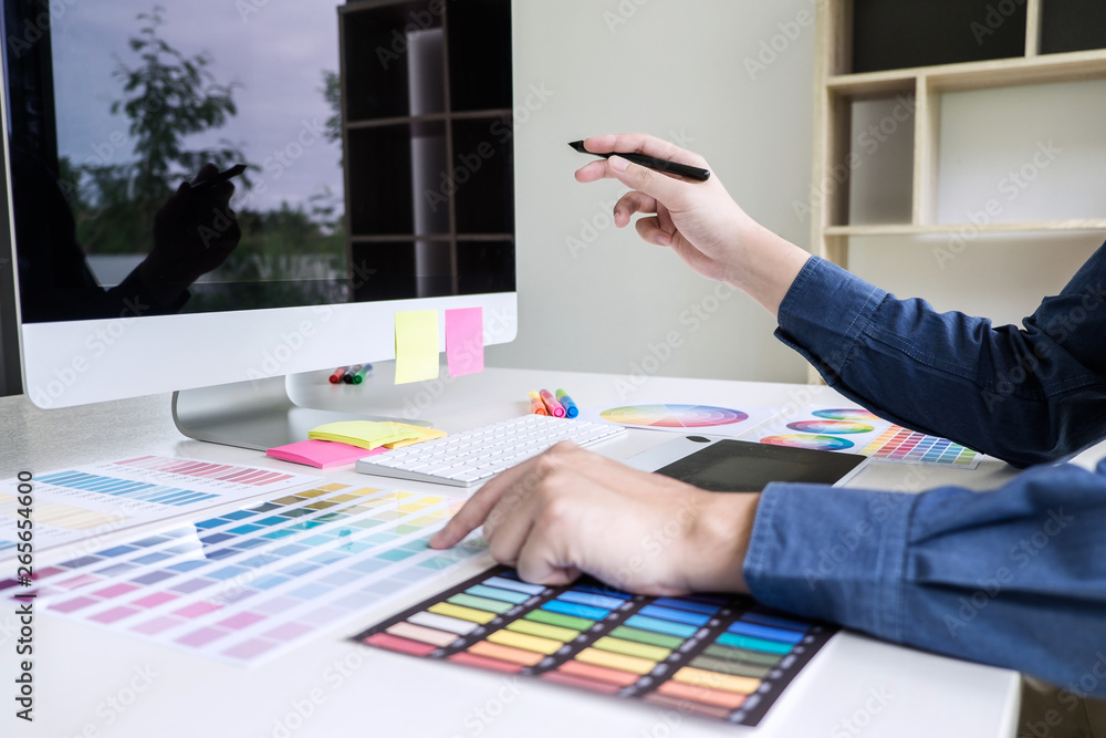 Poster image of male creative graphic designer working on color selection and drawing on graphics tablet at