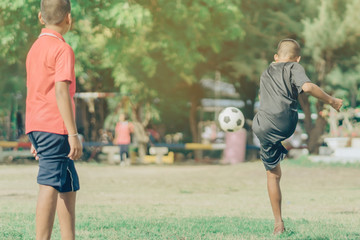 Fototapeta premium Asian boys practice kicking the ball to score goals in the public football field.