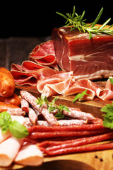 Food tray with delicious salami, pieces of sliced ham, sausages,salad and vegetable. Meat platter with selection