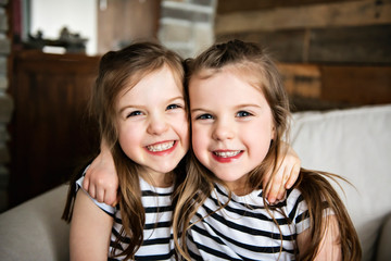 Happy twins embracing each other in the living room