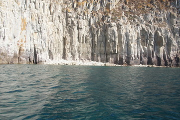 View of the white and yellow mountains of the cliffs growing from the sea on the shore from a boat. Blue Lagoon.