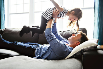 A nice and cool child girl fly with father on the living room