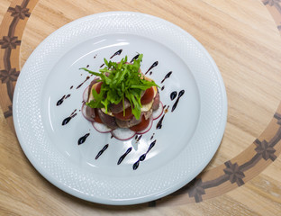 cold cuts with lettuce on a banana leaf, tomato and radish in a plate on a wooden tray